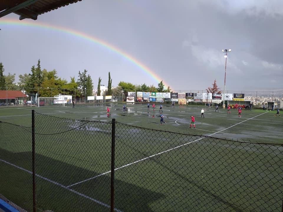 Η ομάδα των Τραχώνων σε αγώνα στο Περιστέρι με ένα μεγάλο ουράνιο τόξο πάνω από το γήπεδο